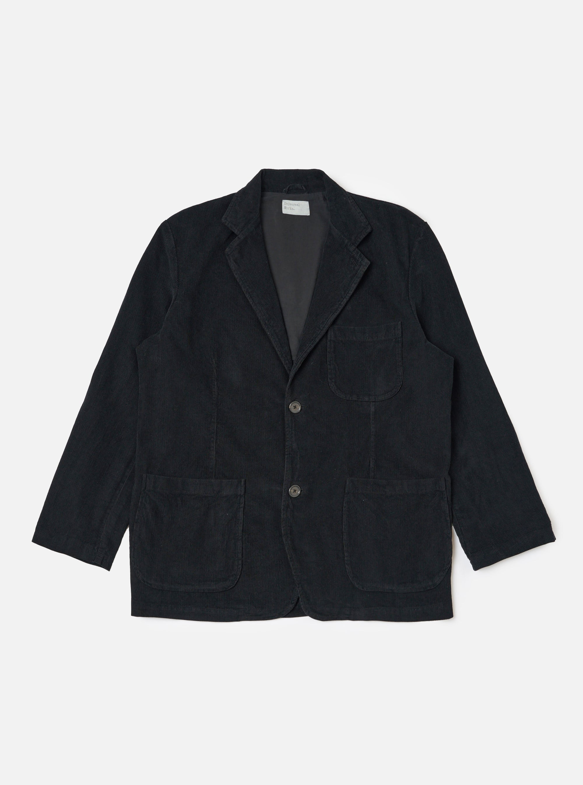 The Black Cat Cord Two Button Jacket in black corduroy, laid flat on a white background. The jacket has two front pockets and a notched lapel.