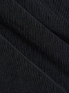 Close-up of the Black Cat Cord Pleated Track Pant fabric. The black corduroy material is draped to show its texture and pleats. 