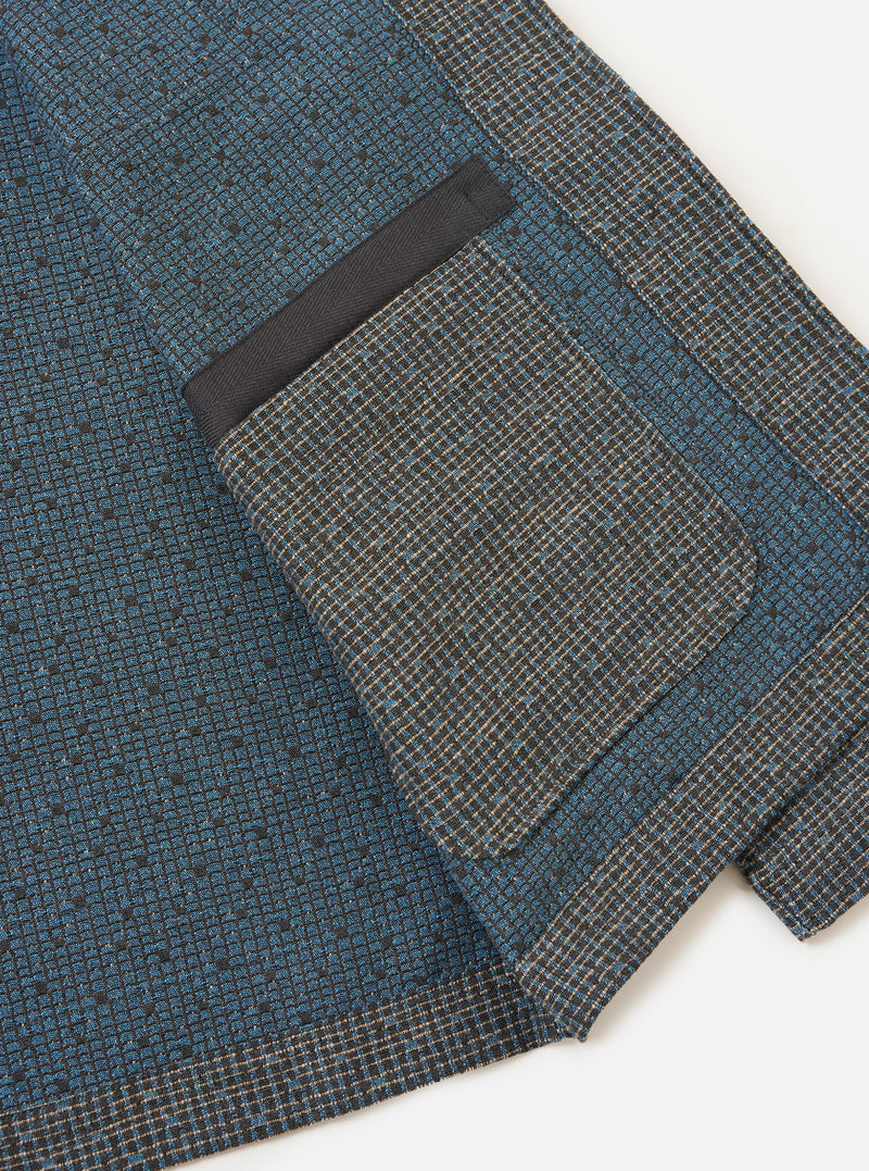 The Grey/Blue Jacquard Weave Field Jacket is shown from the back, laid flat against a solid white background. The image highlights the straight-cut hem, plain cuffs, and the intricate grey and blue textured jacquard pattern throughout the garment.