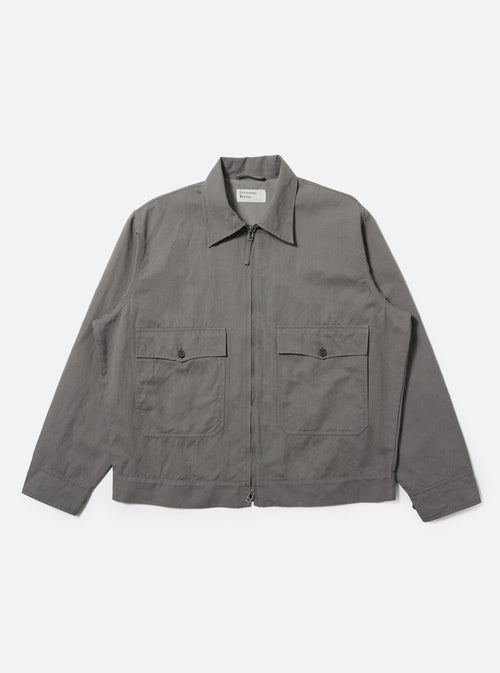 A Mid Grey Linen Slub Weave E130 Jacket is shown laid flat against a solid white background. The jacket features a classic pointed collar, a full button-down front, and two large rectangular patch pockets at the hips. The mid-grey linen fabric exhibits a distinct textured slub weave.
