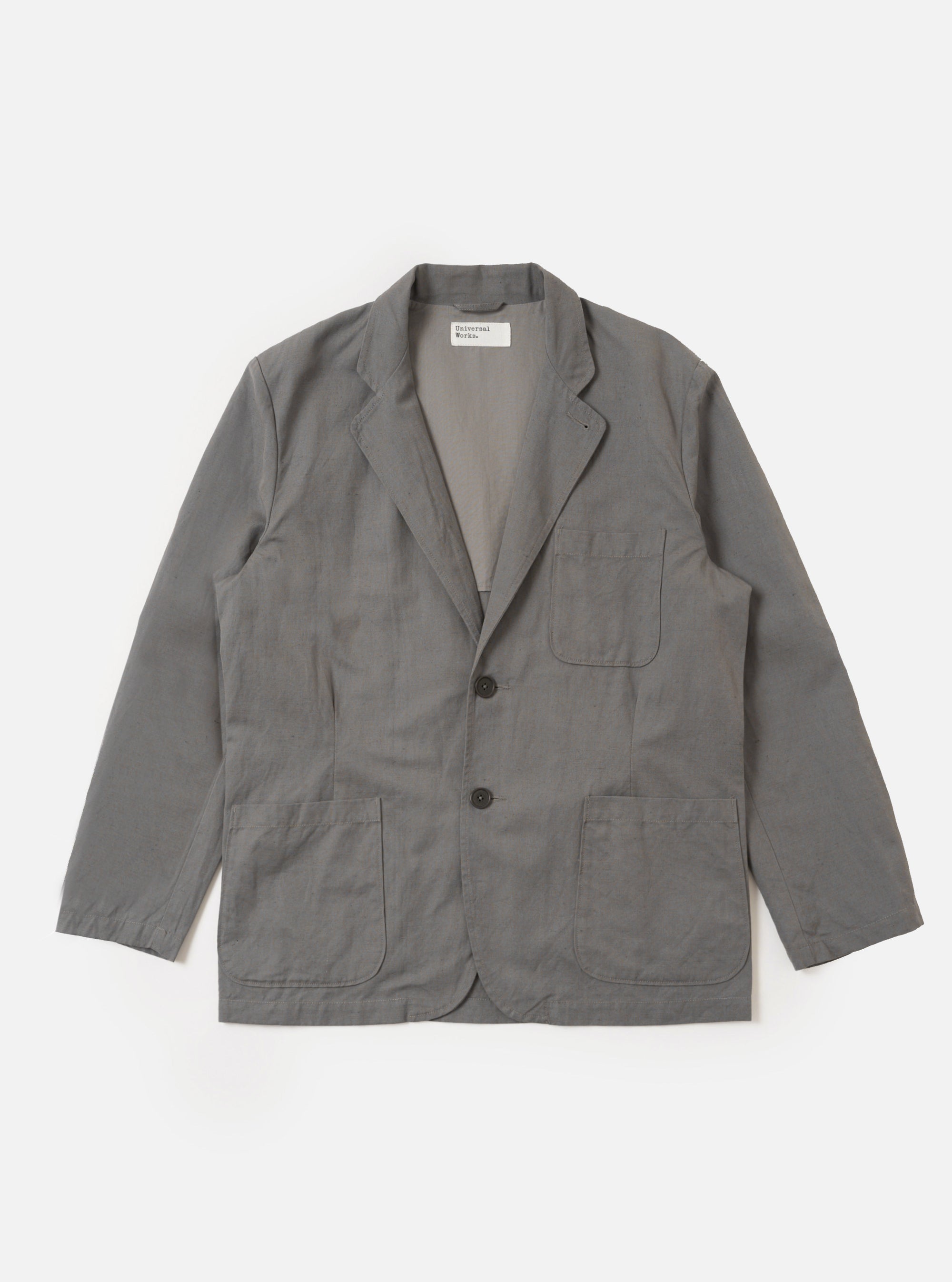 The Mid Grey Linen Slub Weave Two Button Jacket is shown as a flat lay against a white background. The jacket features a notch lapel, a two-button front closure, and two large patch pockets at the waist. The fabric has a visible textured slub weave in a mid-grey tone.