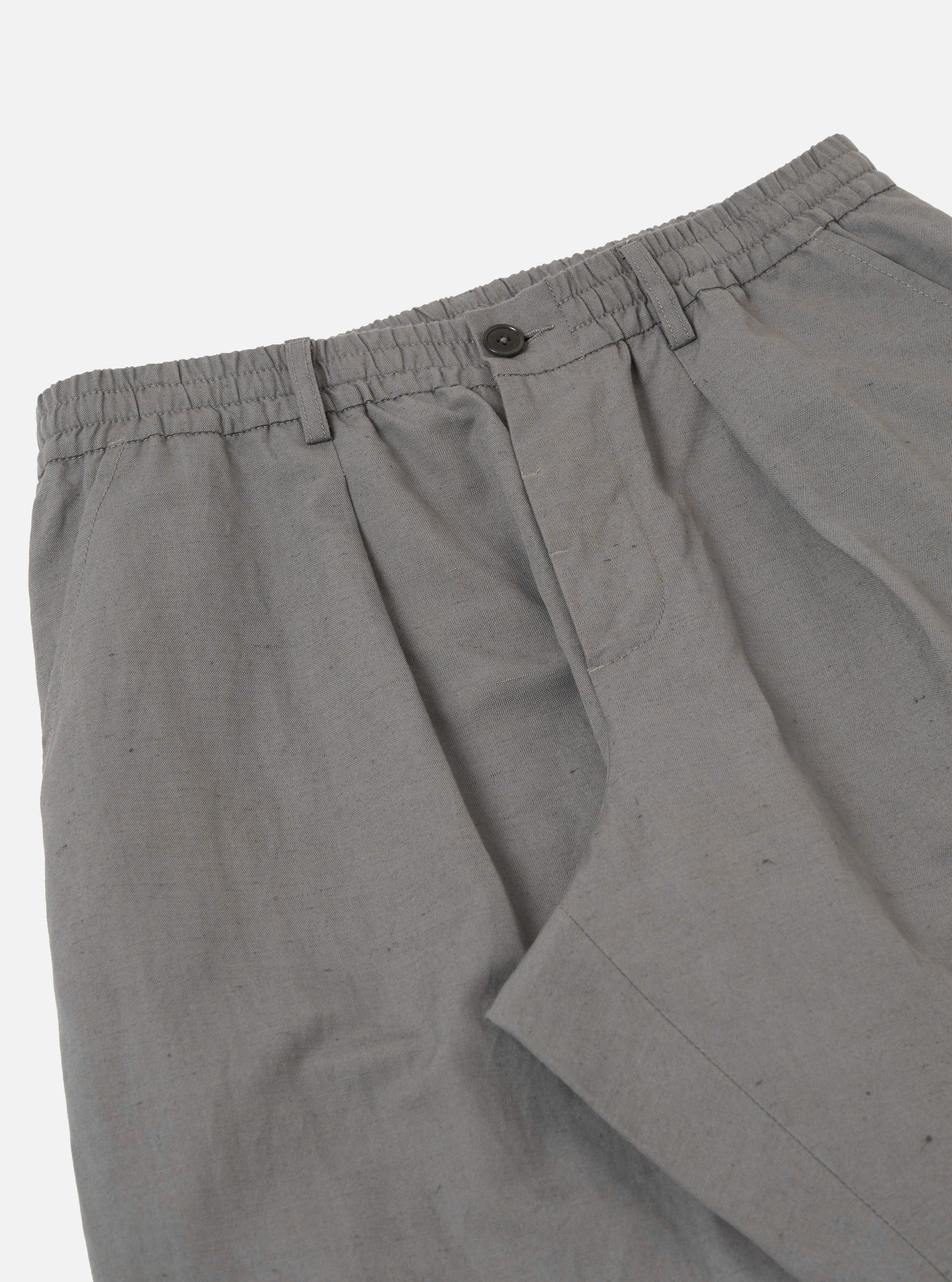 The Mid Grey Linen Slub Weave Oxford Pant is shown from the back as a flat lay against a plain white background. The image highlights the two rear pockets, including one buttoned flap pocket and one buttoned jetted pocket, along with the elasticated portion of the waistband and the textured mid-grey linen fabric.