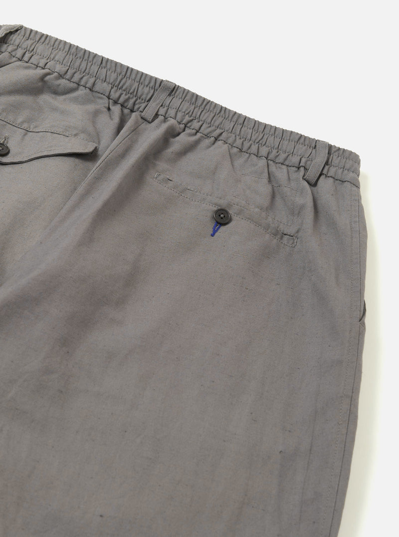 The Mid Grey Linen Slub Weave Oxford Pant is shown from the back as a flat lay against a plain white background. The image highlights the elasticated waistband and the two distinct rear pockets, one with a buttoned flap and one button-jetted. The mid-grey fabric features a visible textured slub weave throughout.