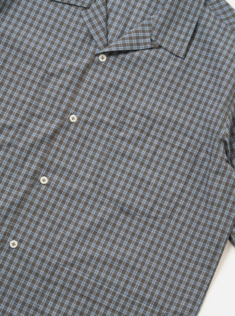 A pale blue check plaid summer overshirt is shown from the back, displayed flat against a plain white background. The image highlights the short sleeves, a straight hem with small side splits, and a horizontal yoke across the shoulders.