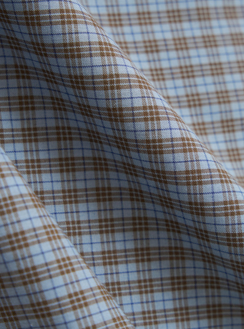 A close-up fabric swatch of the Pale Blue Check Plaid Summer Overshirt is shown, detailing the textured cotton-polyester weave. The pattern consists of a light blue and white checked design with thin orange and navy lines creating a plaid effect. The image focuses solely on the material and its intricate texture.