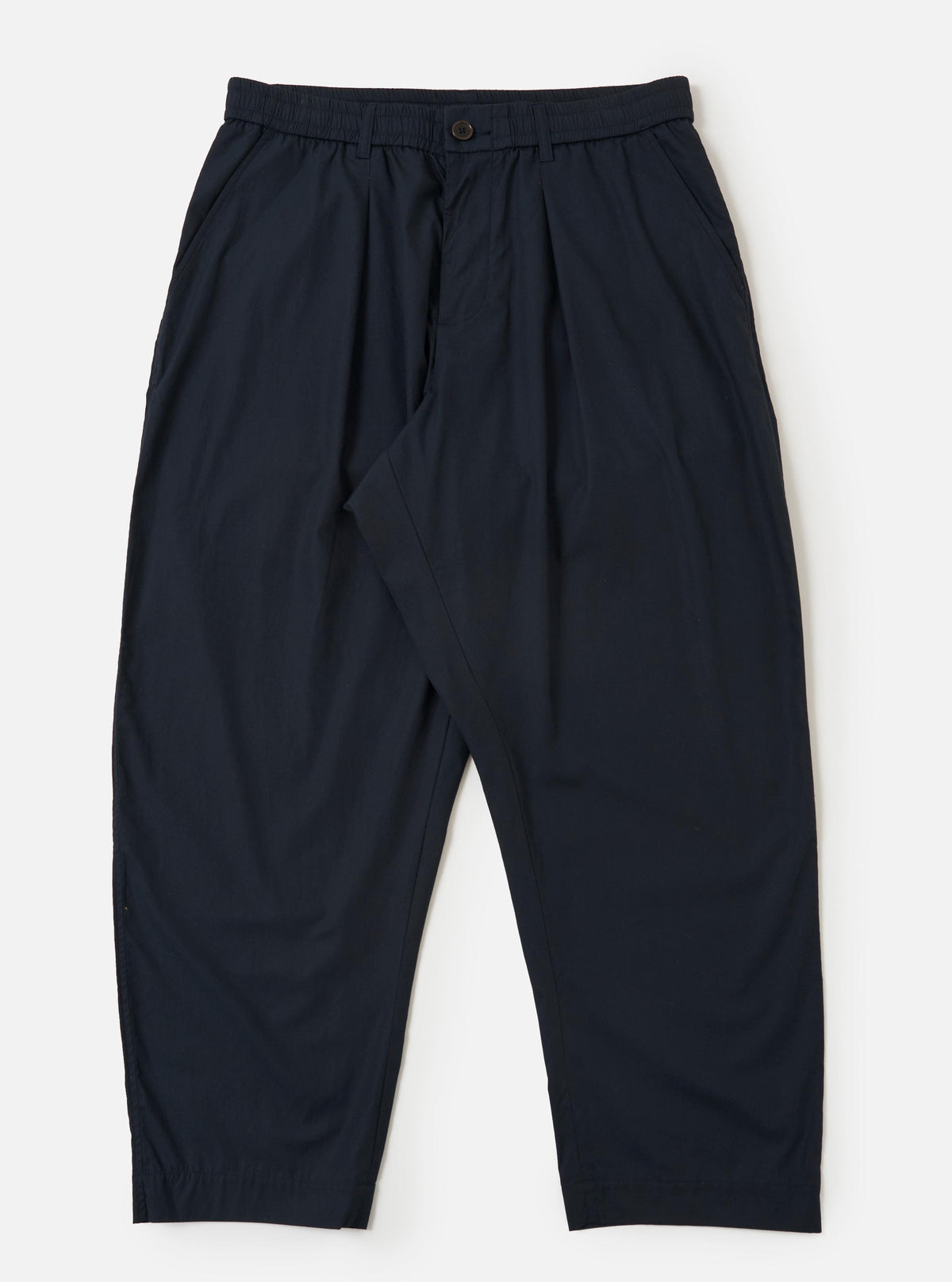 A pair of navy blue cotton broadcloth Oxford pants is displayed flat against a plain white background. The trousers feature a wide leg with a slight taper, a single front pleat, and an elasticated waistband with a white drawstring.