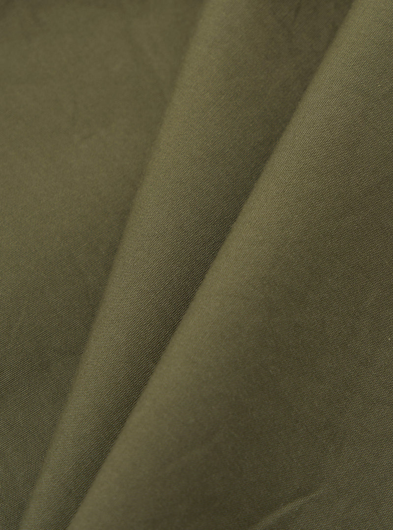 A detailed, close-up fabric swatch of the olive green broadcloth material used for the Olive Broadcloth Oxford Pant. The image highlights the fine, uniform plain weave texture of the cotton fabric.