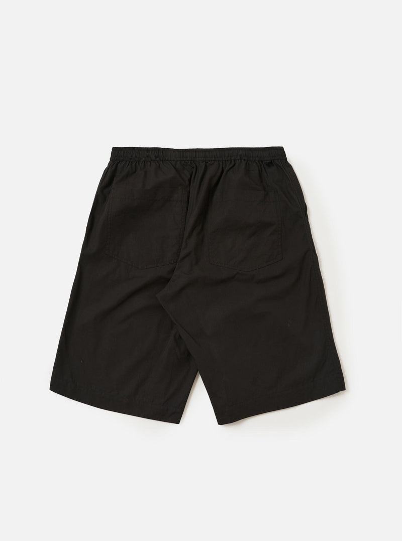 A pair of Black Broadcloth Vacation Shorts is shown from the back, laid flat against a plain white background. The shorts feature a solid black cotton fabric, an elasticated waistband with a drawstring, and a single rear patch pocket on the right side.
