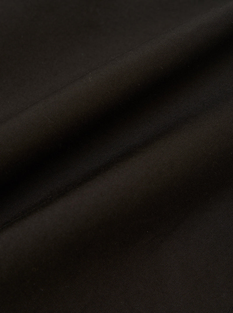 A detailed, close-up fabric swatch of the black cotton broadcloth used for the Vacation Short. The image highlights the fine, tight weave and smooth matte finish of the fabric.