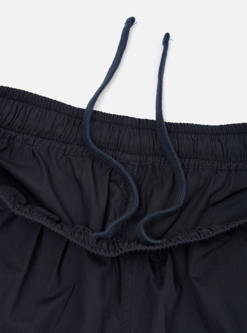 A pair of Navy Broadcloth Vacation Shorts is shown from a close-up perspective, highlighting the texture of the navy blue cotton fabric and the stitching details of a pocket. The garment is laid flat against a plain white background.