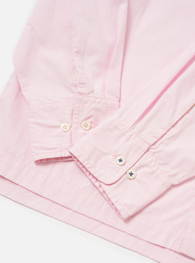 The Pale Pink Broadcloth Lucky Shirt is shown from the back, laid flat against a plain white background. The image highlights the construction of the back yoke and a central box pleat designed for a relaxed fit. The garment is made from a smooth, pale pink cotton broadcloth.