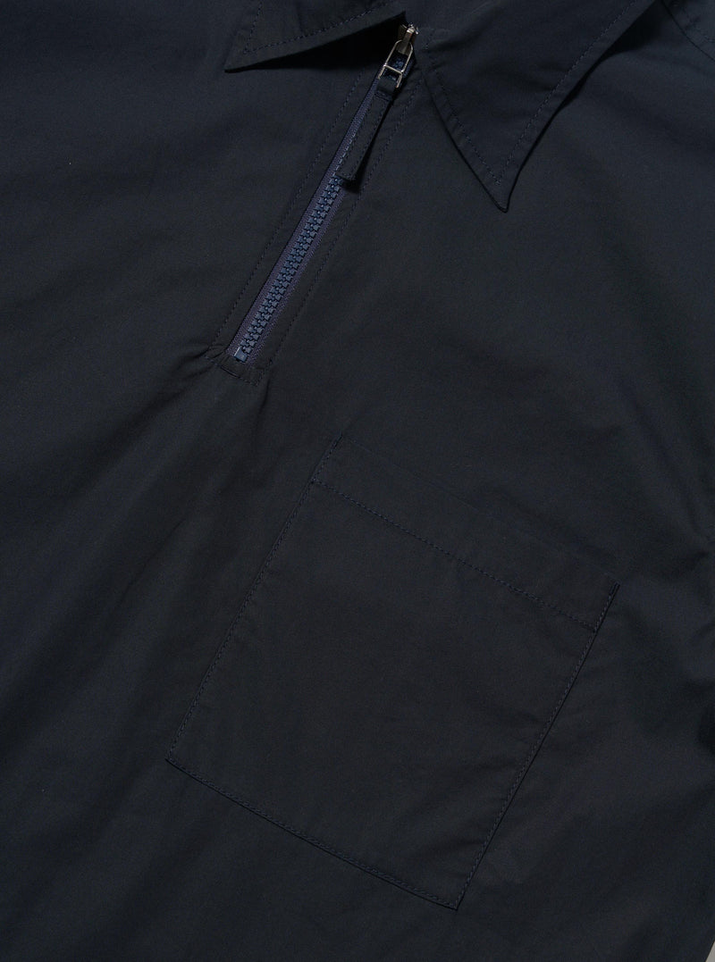 The Navy Broadcloth Ewan Shirt is shown from the back, displayed flat against a plain white background. The image highlights the short-sleeve silhouette, a straight hem with small side splits, and a horizontal yoke across the shoulders with a central box pleat.
