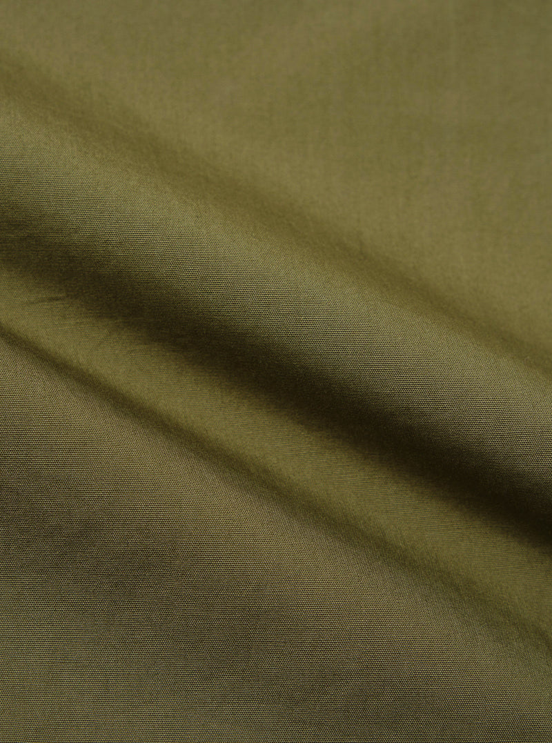 A close-up fabric swatch of the olive green broadcloth used for the Ewan Shirt. The image displays the smooth, tight weave and solid olive color of the material.
