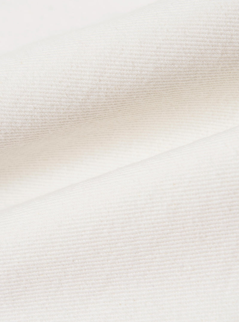 A close-up fabric swatch of the Ecru Slub Drill Dizzy Trouser displays the textured, off-white cotton material. The image highlights the characteristic slubby weave and durable drill construction of the fabric.