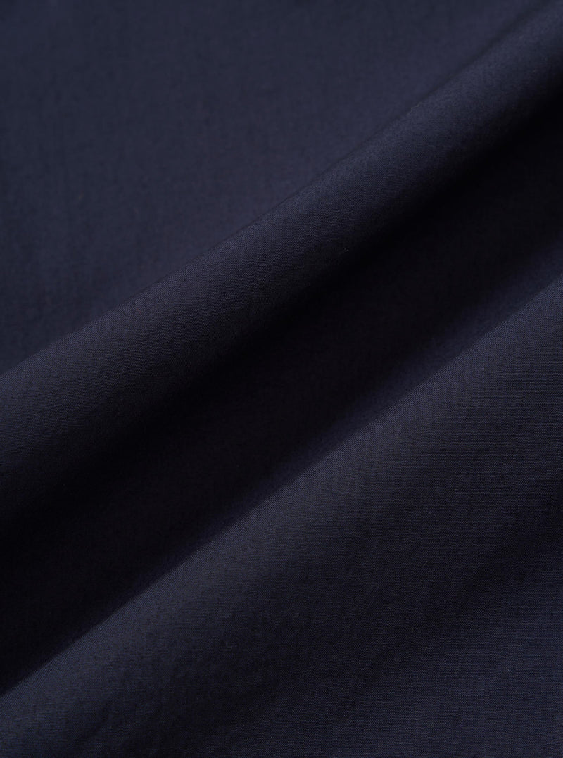 A close-up fabric swatch of the Navy Paper Touch Cotton S/S Fatigue Shirt highlights the smooth, tight weave and deep navy blue color of the material. The image focuses entirely on the texture of the 100% cotton fabric.