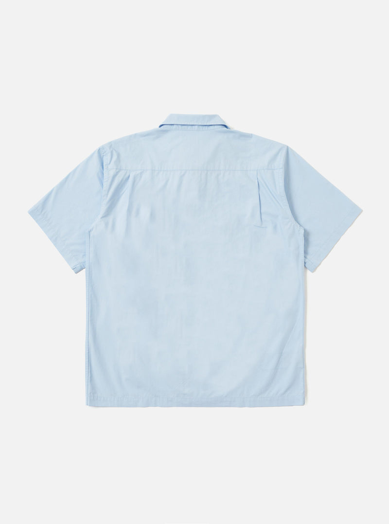 The Sky Blue Paper Touch Cotton S/S Fatigue Shirt is displayed flat against a plain white background. The shirt features a crisp sky blue cotton fabric, a classic pointed collar, a full button-down front, and two large utility-style patch pockets on the chest. The short sleeves and straight hem are clearly visible.