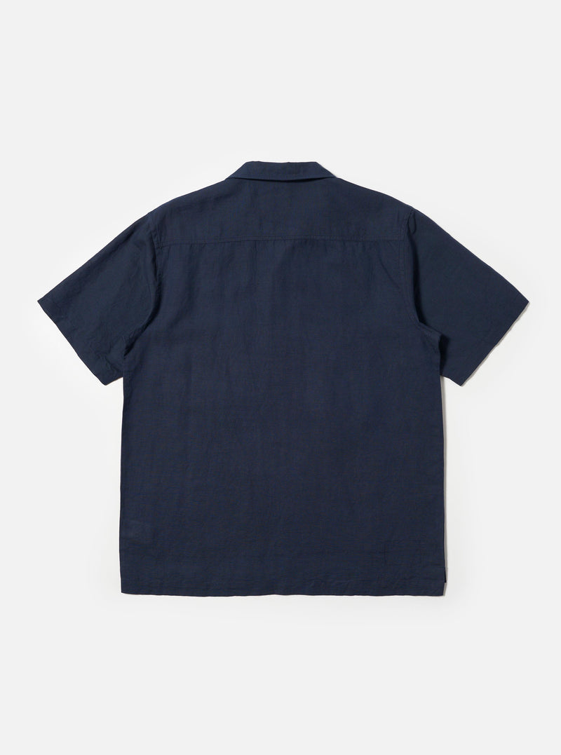 A male model is wearing the Navy Linen Cotton Shirting Camp Shirt against a plain white background. The shirt features short sleeves, a classic camp collar, and a button-down front. The model is shown from the chest up, highlighting the fabric texture and the relaxed fit of the collar. No mannequin is present in the image.