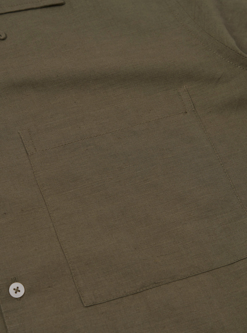 A rear view of the Olive Linen Cotton Shirting Camp Shirt is displayed flat against a plain white background. The image highlights the horizontal back yoke and the straight hemline of the garment.