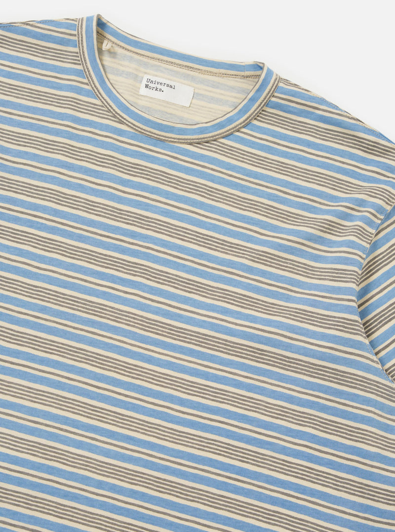 The Pale Blue OS Stripe Jersey Core Tee is shown from the back, laid flat against a plain white background. The image highlights the horizontal light blue and white stripes, the short sleeves, and the straight hem of the garment.