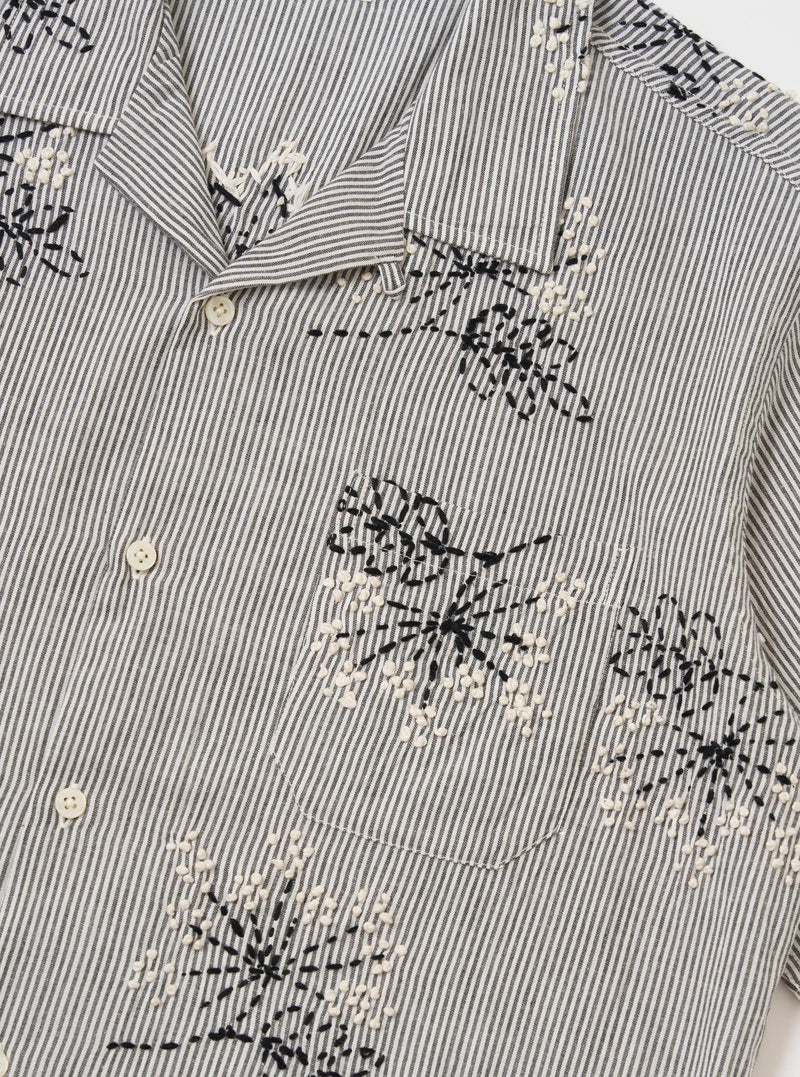 The Grey Hand Embroidered Stripe Cotton Road Shirt is shown from the back, displayed flat against a plain white background. The image highlights the horizontal hand-embroidered stripe pattern in grey and white, the short sleeves, and a straight hem.