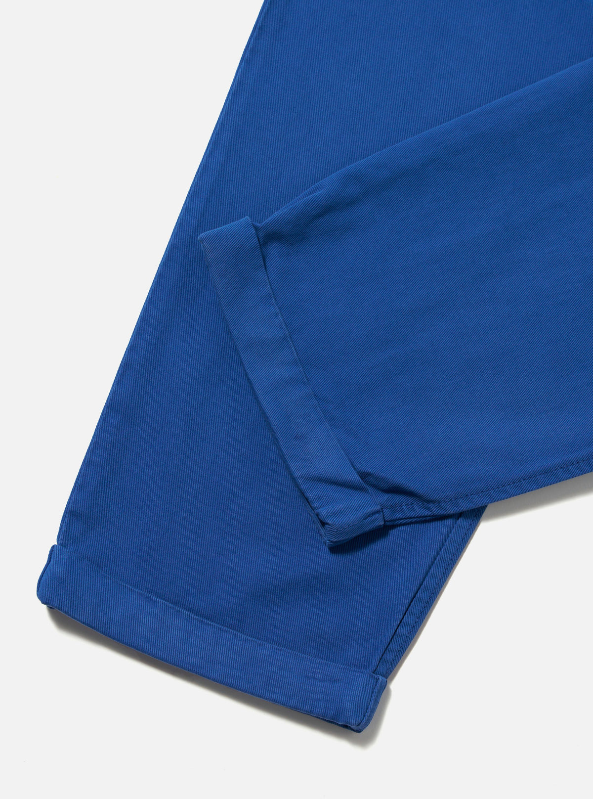 Close-up of the Navy Derek Twill Super Chino on a white surface. The twill fabric is a vibrant navy blue, and the pants have a modern, tailored fit.