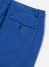 Close-up of the Paraboot x Universal Works Navy Derek Twill Super Chino. The twill fabric is a vibrant blue. Back pocket detail with button closure. Shot on a white background.