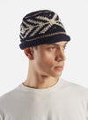 An angled side product shot of the cableami® Navy Wool Jacquard Watch Cap on a plain white background, showcasing the knit structure, turn-up rim, and subtle pattern texture around the crown.