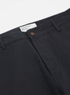 Close-up of Black Twill Military Chino pants on a white background. The twill fabric is visible, showcasing the fit and material. The Universal Works label is visible.