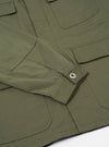 Close-up of the Light Olive Twill MW Fatigue Jacket showing the twill texture, pockets, buttoned sleeve, and seams. The jacket is laid flat on a white surface.