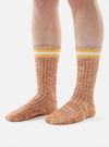 Close-up of a model wearing Yellow Cotton Everyday Stripe Sock on a white background. The socks are orange with yellow and white stripes at the top.