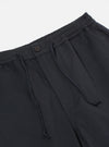 Close-up of the Black Twill Hi Water Trouser on a white background. Shows the elastic waistband, drawstring, button, and twill fabric.