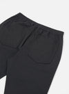Close-up of the back of Black Twill Hi Water Trouser on a white surface. Features an elastic waistband and back pockets.