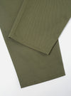 Close-up of the Light Olive Twill Hi Water Trouser on a white surface. The twill fabric is visible, showcasing the texture and color of the trousers.