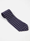 Close-up of a Navy Dot Print Tie on a white surface. The tie is navy blue with white polka dots. The fabric has a smooth, slightly shiny appearance.