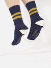 A model wears Navy/Yellow Cotton Rib Sport Sock on a white background. The socks are ribbed with yellow stripes and have white accents on the heel and toe.